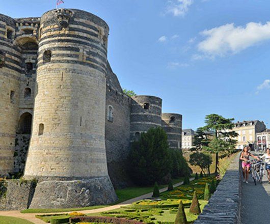 Le château d'Angers avec touristes à vélo à côté 