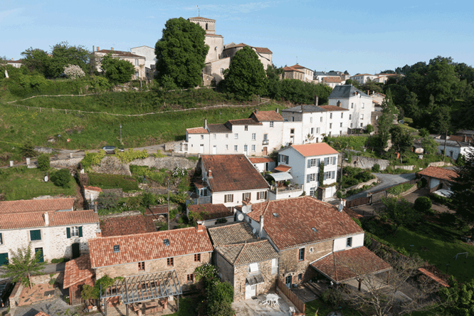 Village avec toits en brique et verdure, colline