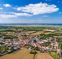 vue aérienne d'un village aux maison de tuiles, bordé de champs